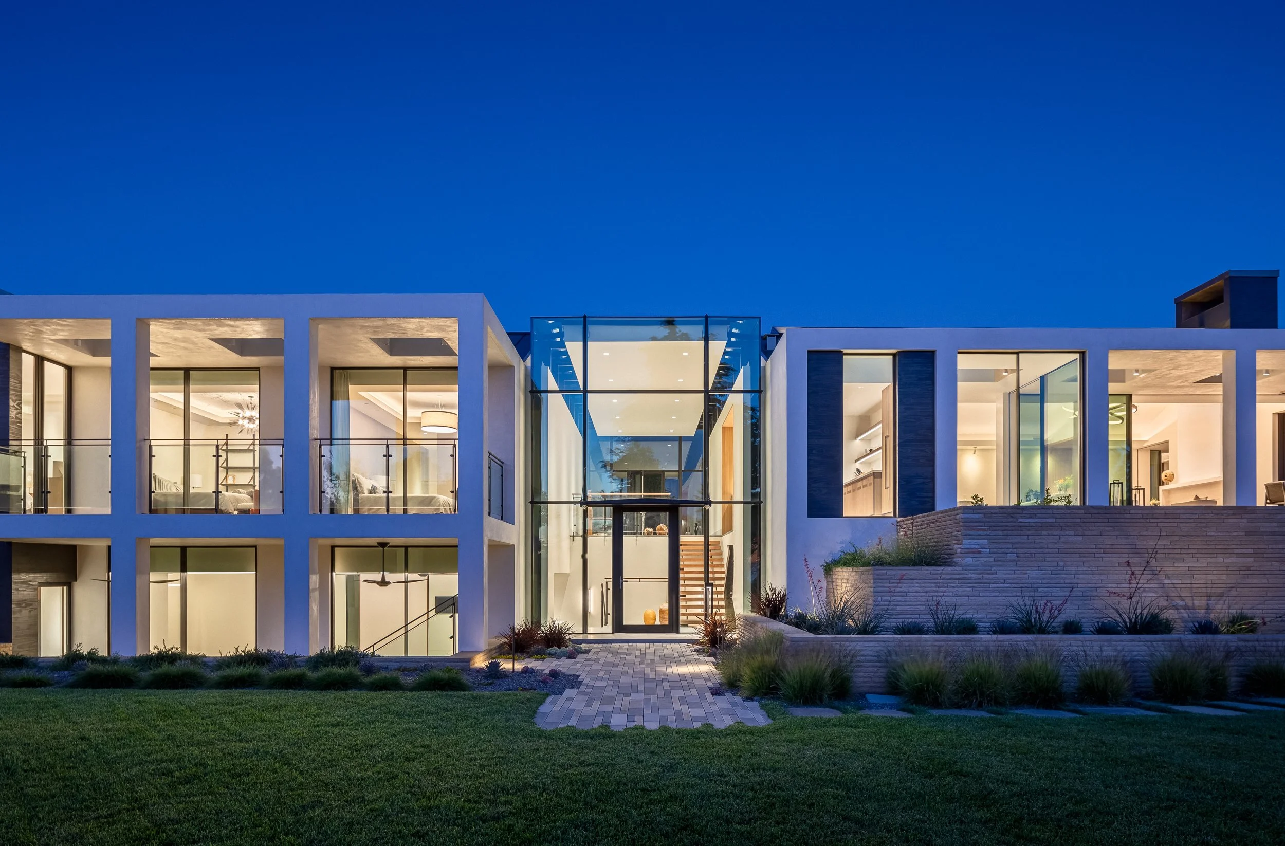 Modern luxury home with large windows and glass entrance at dusk.