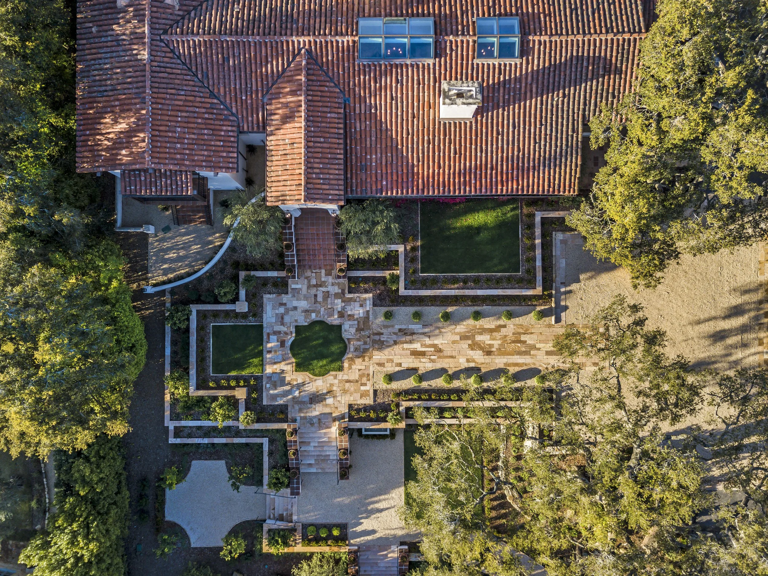 Aerial view of a luxurious Mediterranean-style residence, showcasing its terracotta-tiled roof and meticulously landscaped garden.