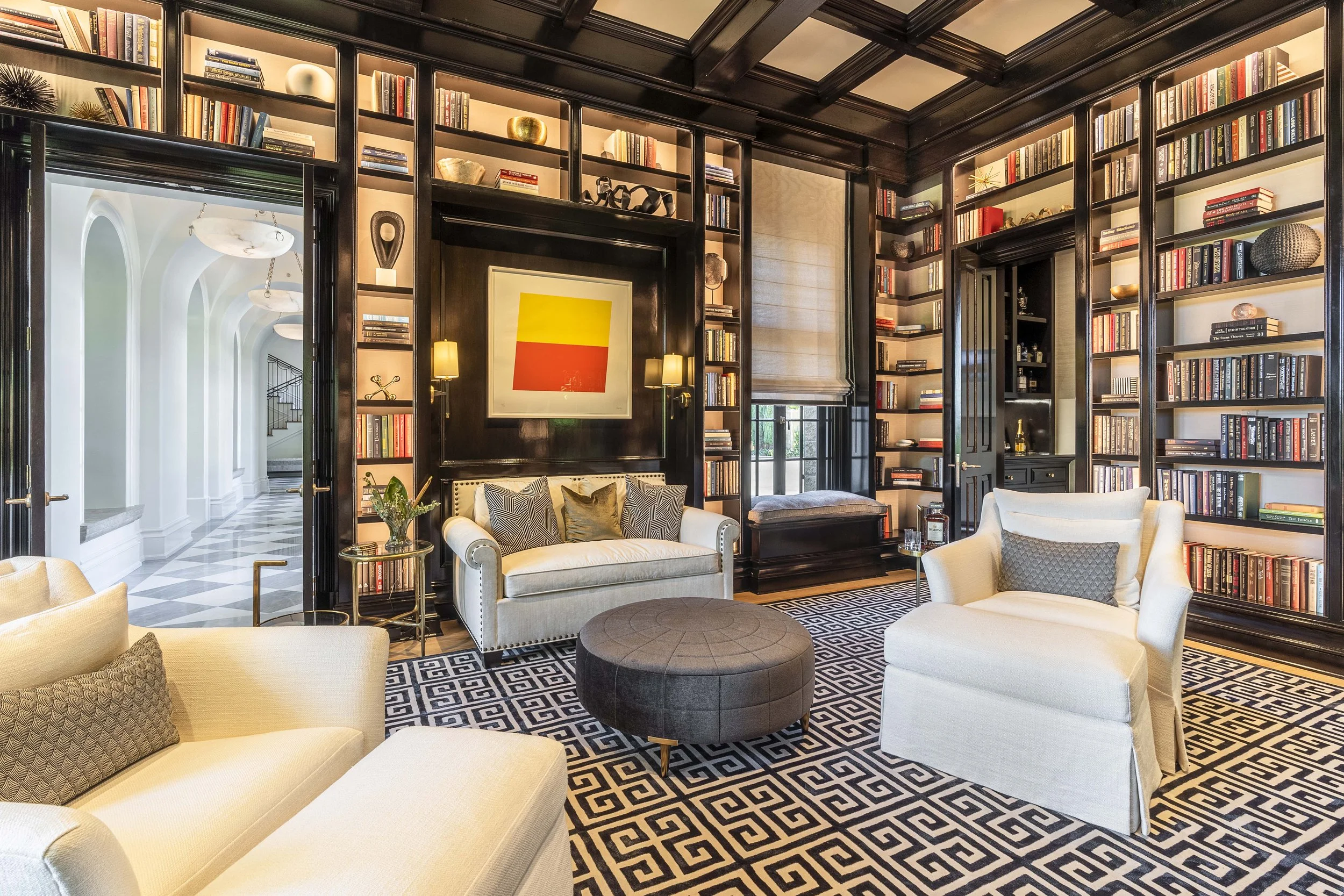 Luxurious home library with custom-built shelves, modern artwork, and plush seating, designed by The Warner Group Architects, Inc.