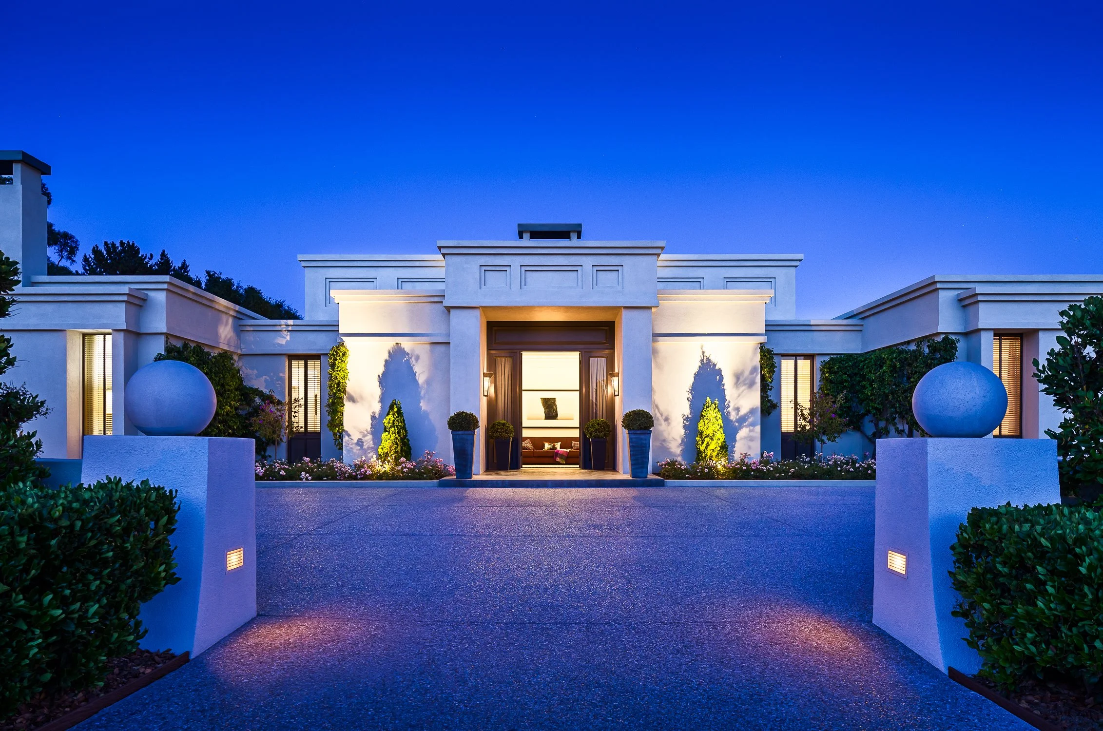 Modern luxury home exterior at dusk with landscaping and lighting.
