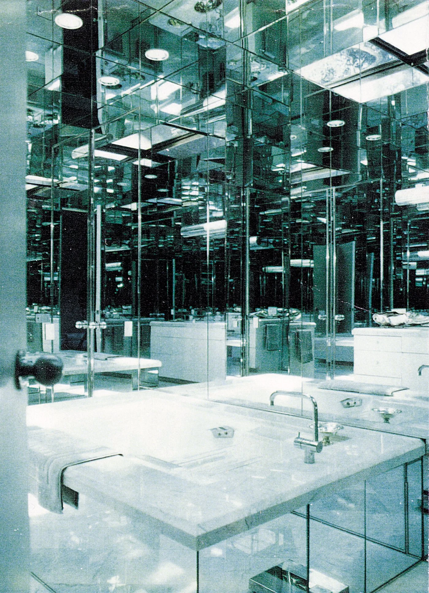 Bathroom with mirrored walls and ceiling, marble countertops, and silver fixtures.