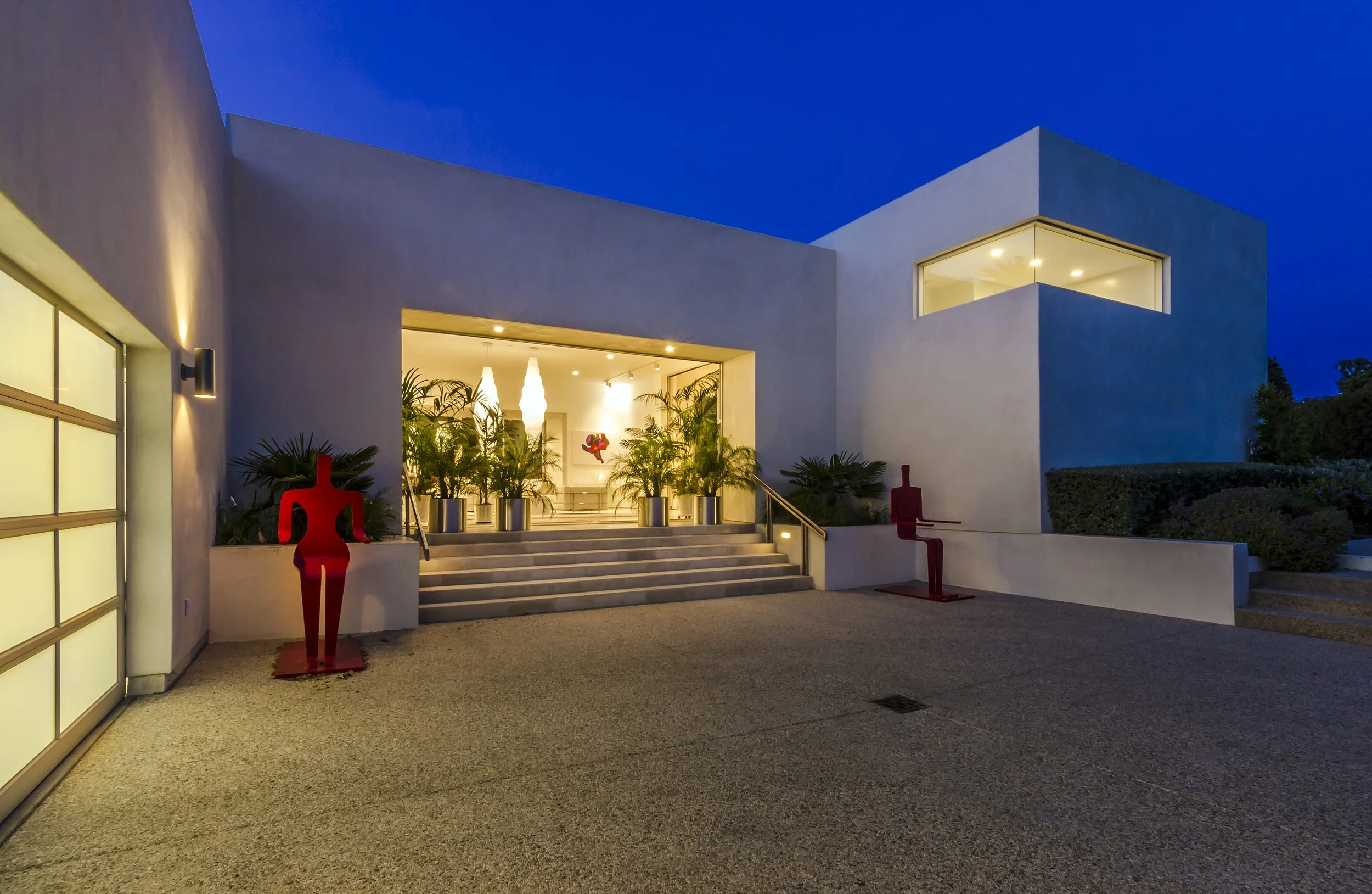 Modern architectural entry featuring clean lines and bold red sculptures near the stairs.