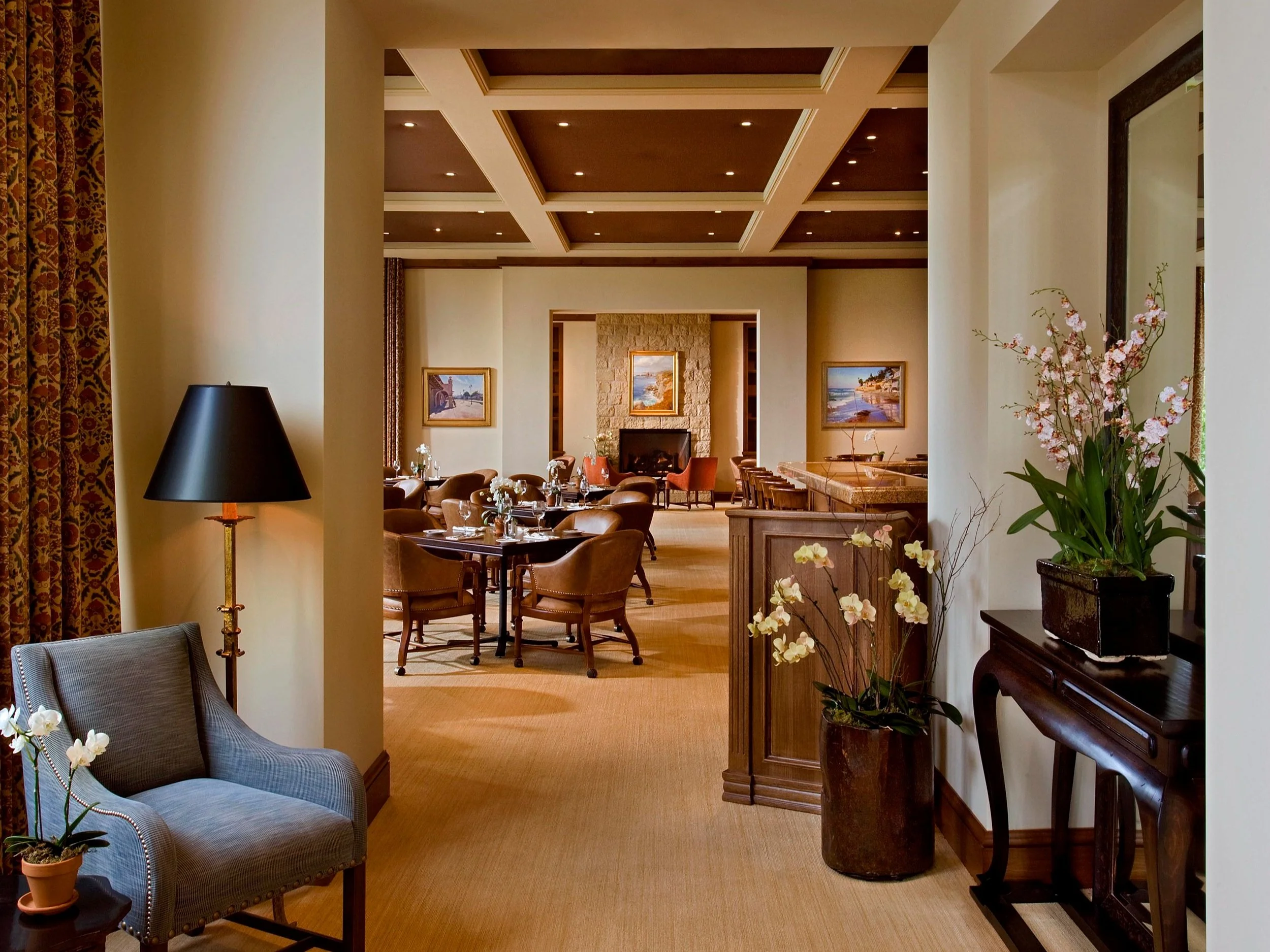 Elegant dining area at Birnam Wood Country Club featuring leather chairs, a cozy fireplace, and sophisticated decor with large windows overlooking the golf course.