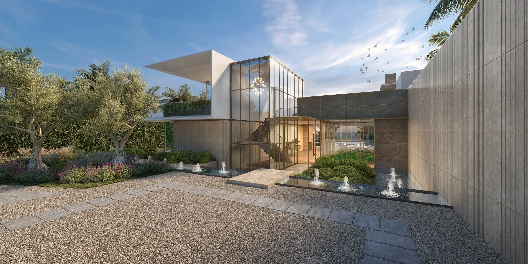 Modern luxury home with a grand entrance featuring large glass windows, a floating staircase, and a minimalist water fountain. The landscape includes olive trees, lavender, and manicured gardens, blending nature with contemporary design.