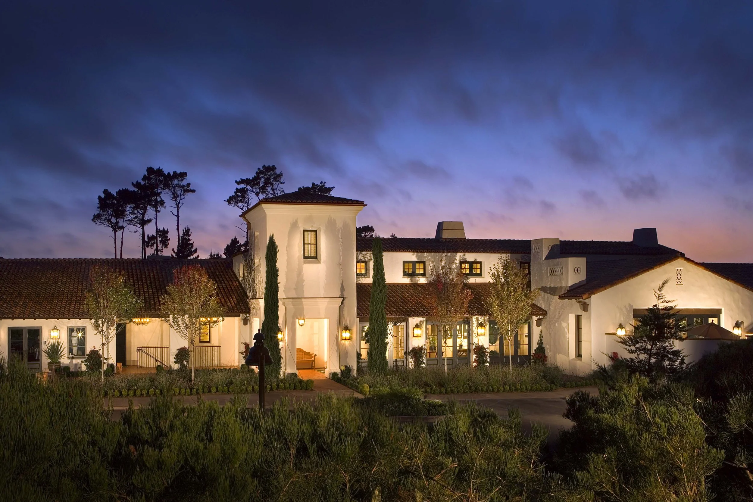 Monterey Peninsula Country Club exterior at sunset showcasing Mediterranean-style architecture with terracotta roof tiles and elegant landscaping.